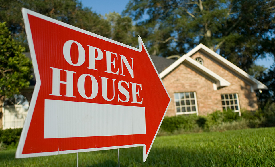 a home with an open house sign in the front lawn